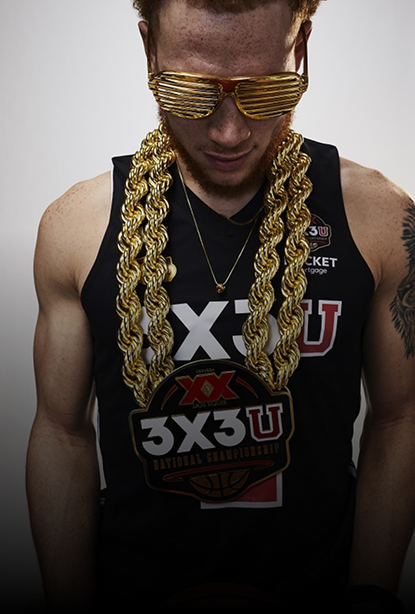 A man wearing a black 3X3U basketball jersey, draped in two thick gold chains 