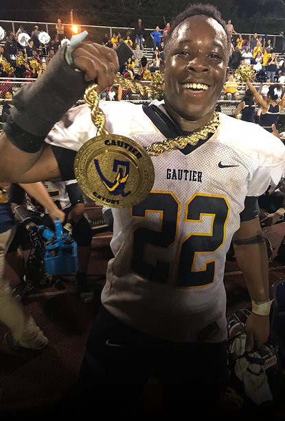 A smiling football player a gold championship medallion. 